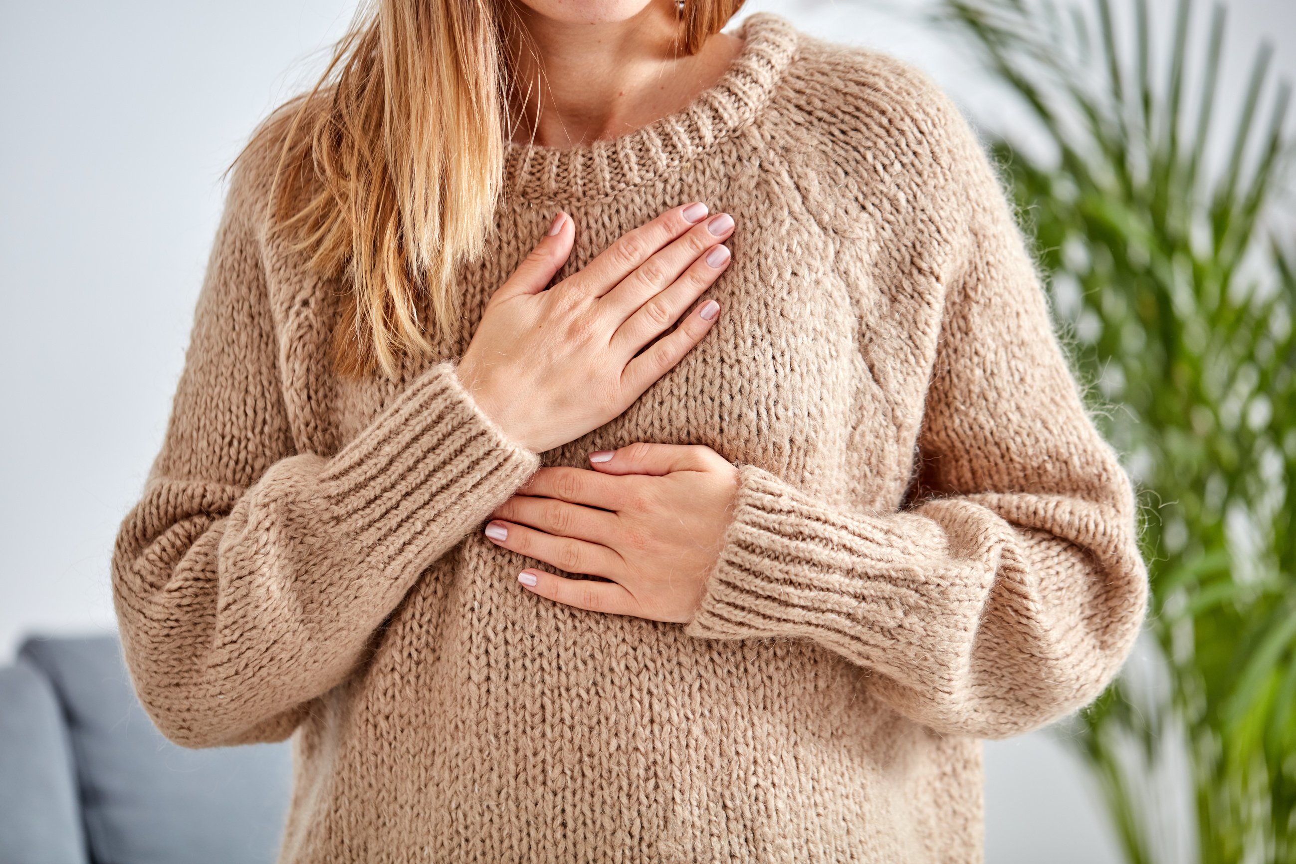 Young woman with heart problem holding chest.